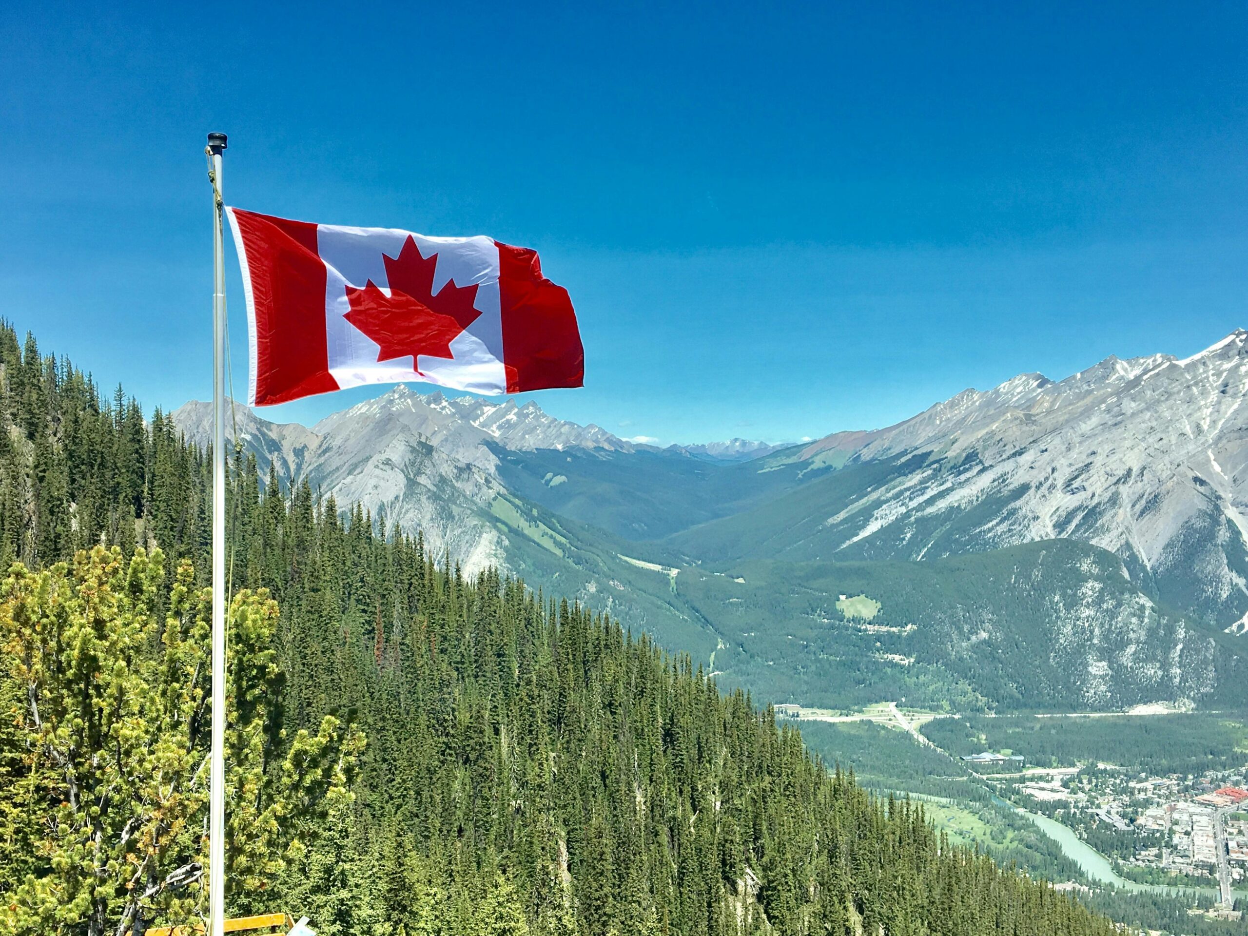 Canada flag with mountains and forest in the background.